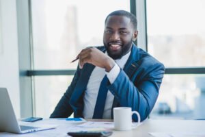 man in a suit sitting in the office and smilling